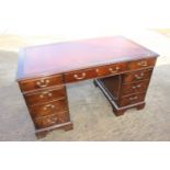 A mahogany double pedestal desk with tooled red leather top, fitted nine drawers, on bracket feet,