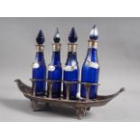 A Bristol blue glass bottle cruet set with silver mounts and labels, on a silver plated base