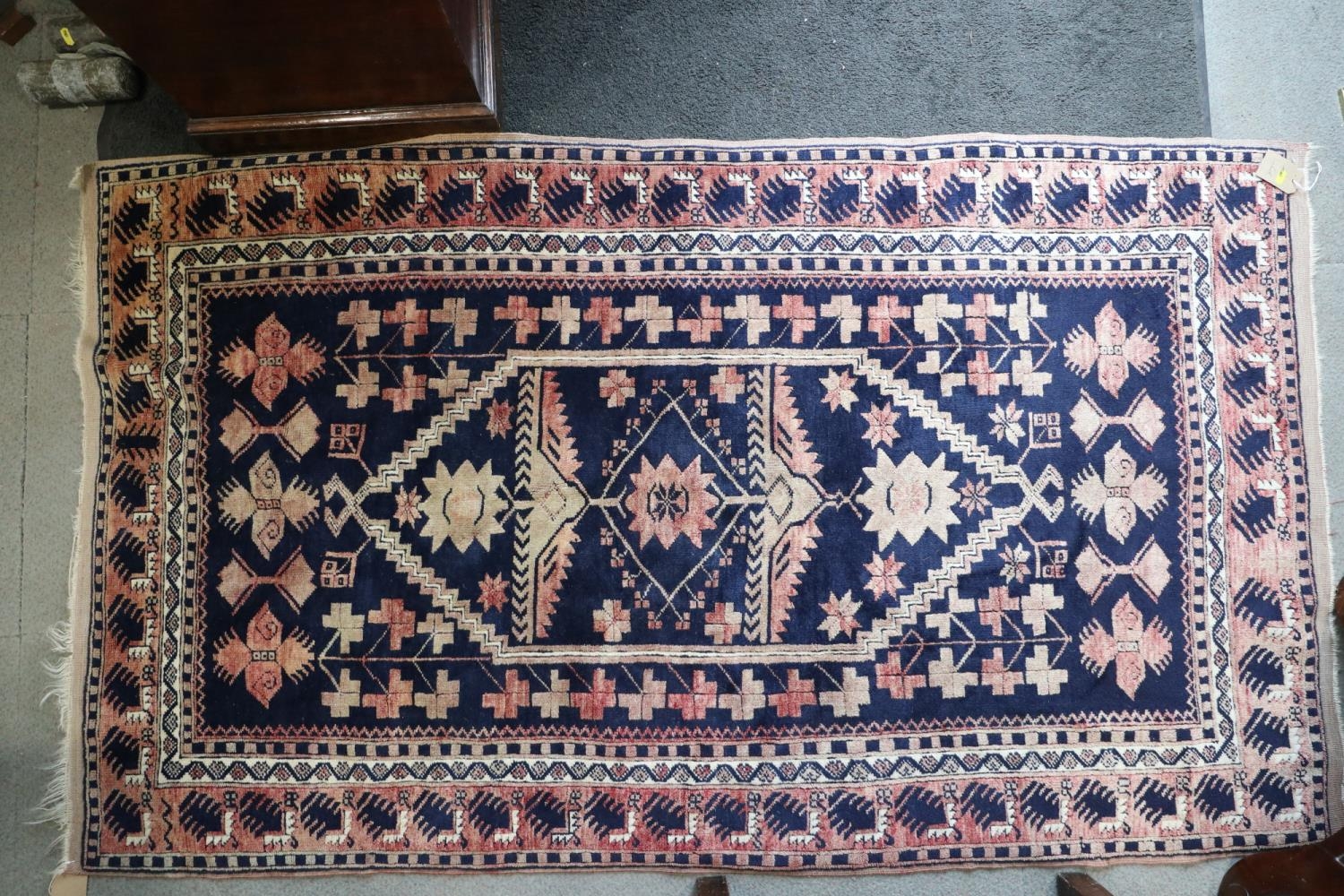 A Caucasian tribal rug with stylised floral centre on a blue ground and multi-bordered in shades