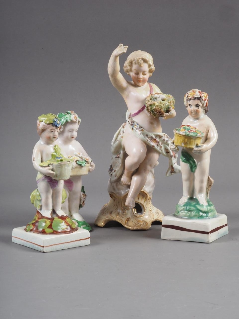 A Derby porcelain cherub with basket of flowers, 4" high, two similar figures, 4 1/2" high and 4"