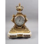 A brass mantel clock with Roman numerals and urn finial, on white marble stand, 12 1/2" wide
