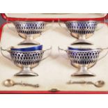 A set of four early 20th century two-handled oval salts with blue glass liners and matched spoons,