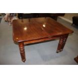 An early 20th century walnut extending dining table with two extra leaves, on six reeded turned