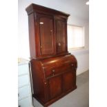 A mid Victorian mahogany cylinder bureau bookcase, the upper section enclosed two glazed panel