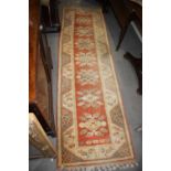 A Kazak runner of traditional design, with seven star  medallions in shades of rust, tan, grey and