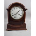 A mahogany cased arch top mantel clock with enamel dial and Roman numerals, 12" high