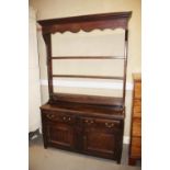An antique oak dresser, fitted open plate rack, over two drawers and cupboards enclosed two paned