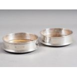 A pair of silver bottle coasters with turned bases
