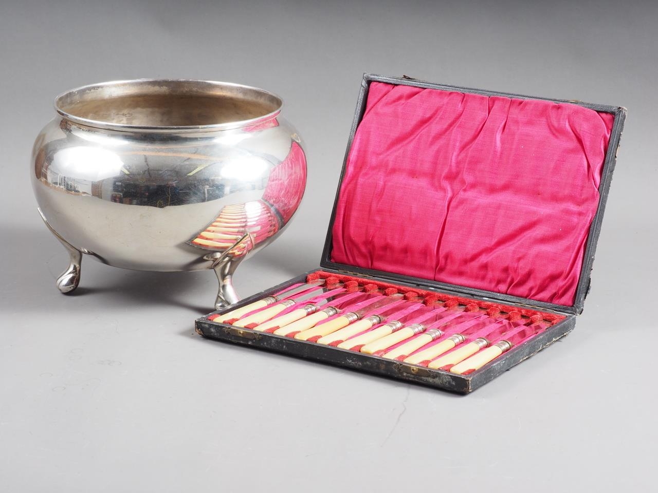 A silver plated bowl, on three ball feet and a set of tea knives, in case