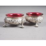 A pair of Victorian silver salt cellars with embossed floral decoration, on paw supports, 4oz troy