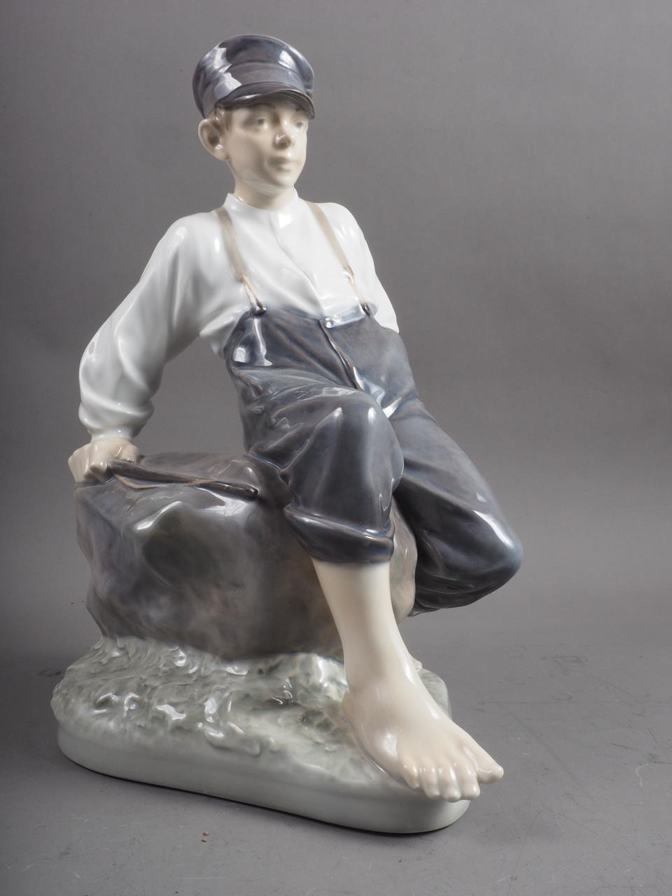 A circa 1960s Royal Copenhagen figure of a shepherd boy sitting on a rock, 12 1/2" high