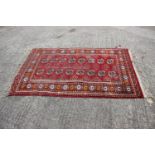 A Bokhara wool rug with sixteen elephant guls, geometric designs and multi-bordered in shades of