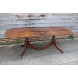 A mahogany and banded double pedestal dining table with extra leaf, on tripod splay supports, 84"