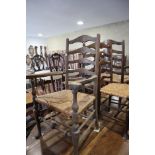 A pair of ladder back carver chairs with rush envelope seats, on turned and stretchered supports,
