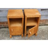 A pair of 1930s light oak bedside cupboards, fitted shelf over one door, on shaped supports, 14"