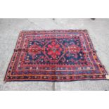 A Middle Eastern wool rug with central medallion, geometric design and multi-bordered in shades of