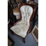 A mahogany spoon back low chair, upholstered in a natural leaf patterned fabric, on cabriole