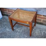 A 1930s oak dressing stool with cane seat, on square taper stretchered supports, 18" wide x 14" deep