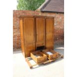 An oak breakfront wardrobe with two hanging compartments flanking cupboard and three drawers, on