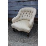 A button backed tub armchair, upholstered in a patterned cream fabric, on castored supports