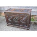 A chip carved oak coffer of 16th century design with three Gothic panel front, on stile supports,