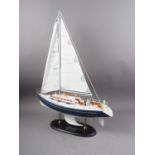 A scale model sailing yacht, on oval ebonised stand, 26" high