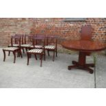 A reproduction polished as mahogany circular  extending dining table with one extra leaf, on faceted