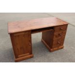 A pine double pedestal desk, fitted cupboard and three drawers, 54" wide x 24" deep x 30" high