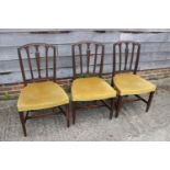 A set of three Sheraton Revival carved mahogany vertical rail back dining chairs with stuffed over