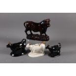 Two black and gilt decorated cow creamers, a white cow creamer and a treacle glazed bull (all with