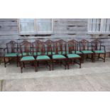A set of twelve mahogany carved wheatsheaf dining chairs with drop in seats, upholstered in a