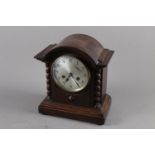 An oak cased arch top mantel clock with barley twist columns, silvered dial and Arabic numerals,