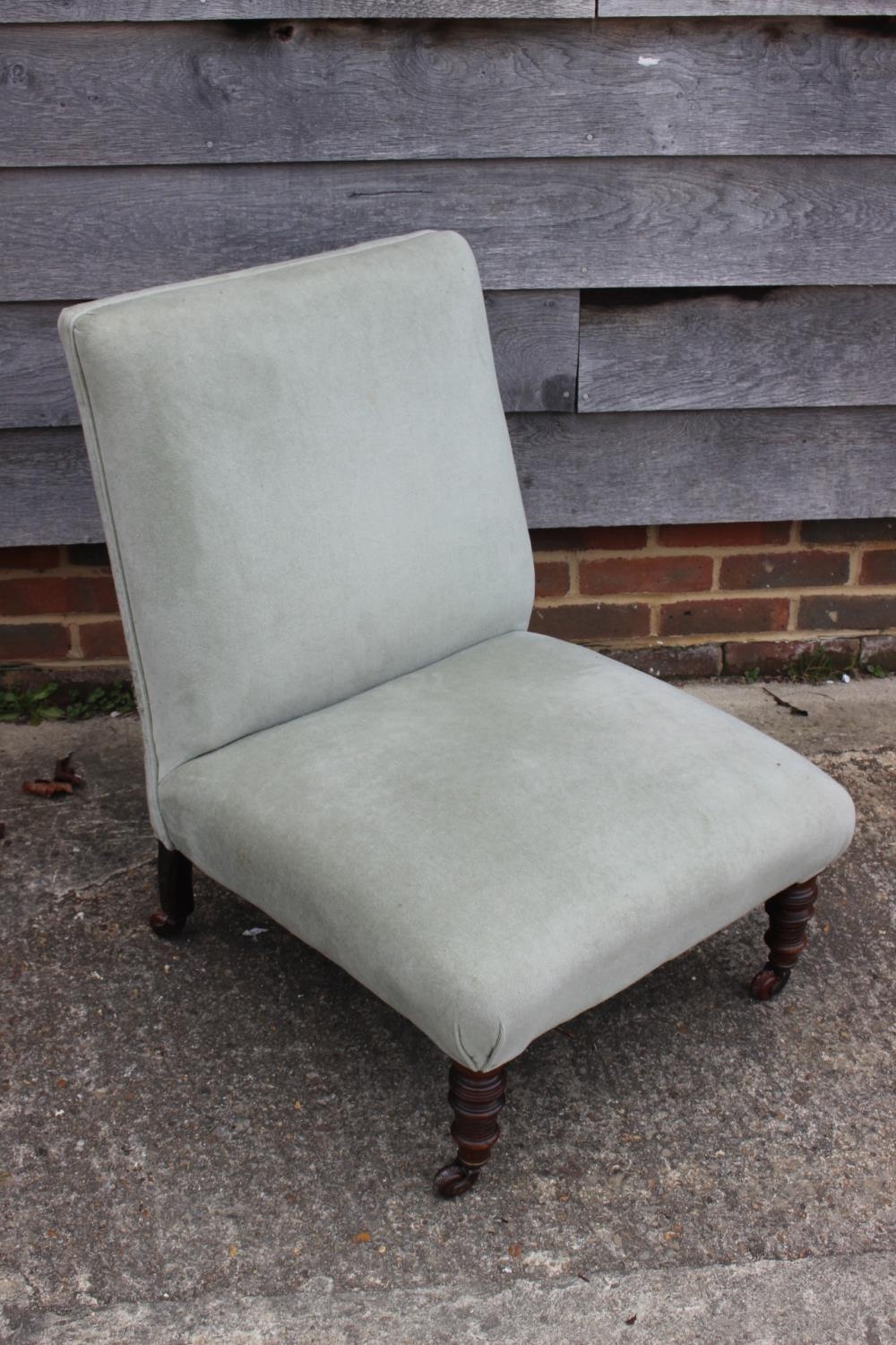 A late 19th century low seat nursing chair, upholstered in a sage green velour, on turned and