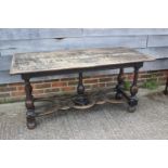 An oak carved table of early 17th century design, on vase turned columns and united by a pierced