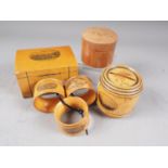 A Mauchline ware money box, 4" wide, a similar money box, three Mauchline napkin rings and a similar