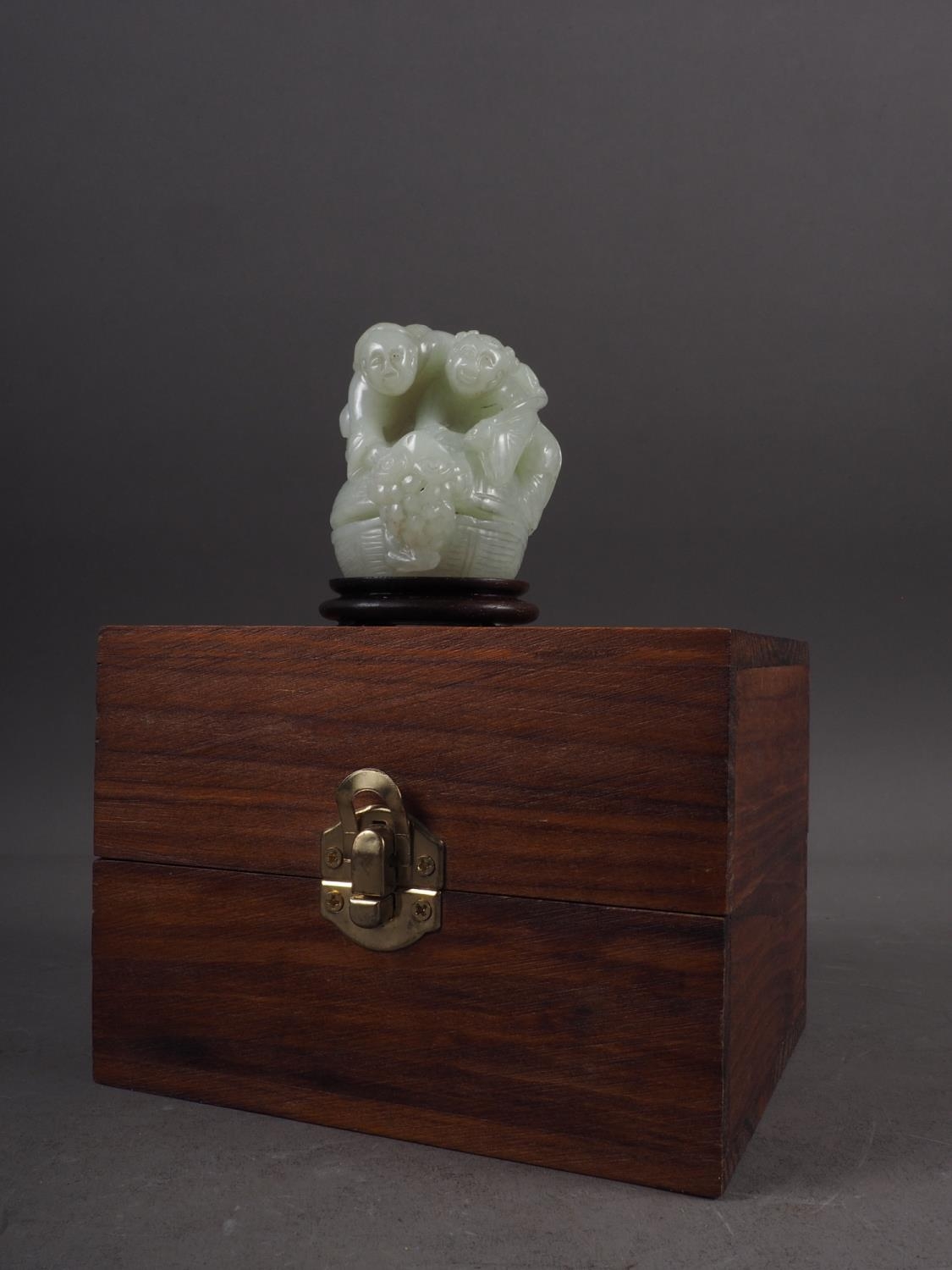 A Chinese carved pale jade figure group, 2 1/2" high, on stand, in a hardwood hinged box