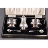 A silver three-piece cruet set and two plated spoons, in fitted case, 4.2oz troy approx