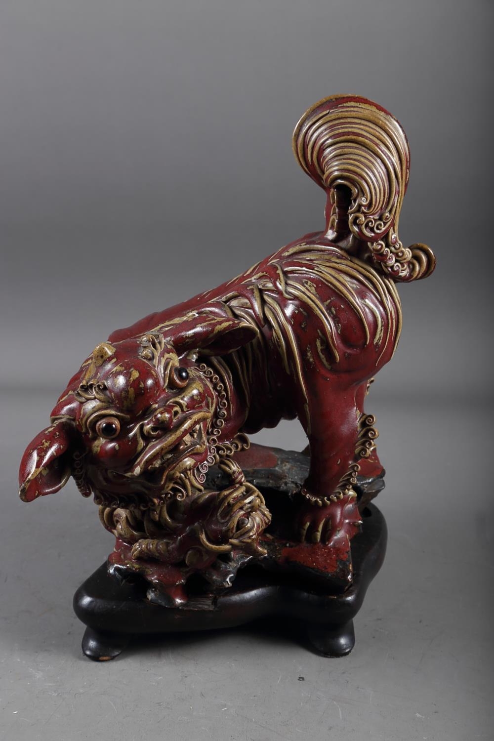 A Chinese red and brown glazed porcelain model of a Dog of Fo, on hardwood stand, 16" high