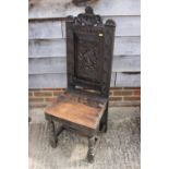 A carved oak hall chair of 17th century design with martlet crest panel back, 45" high