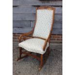 A Victorian carved mahogany scroll arm rocking chair with stuffed over seat and padded back