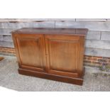 A polished mahogany side cupboard with fitted interior enclosed two panel doors, on block base,