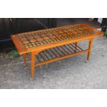 A 1960s teak tile inset top two-tier coffee table, on castored supports, 42" wide x 16" deep x 18"