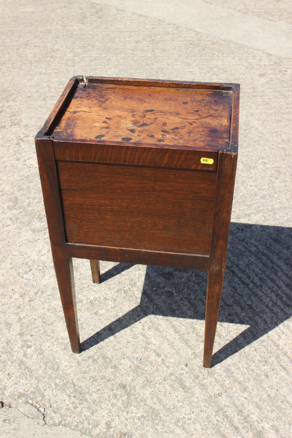 An early 19th century provincial oak tray top bedside cupboard with lift up front, on square taper