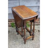 An oak oval drop leaf occasional table, on turned and stretchered supports, 24" wide x 36" deep x