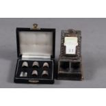 A leather and silver mounted stamp holder and calendar, and six silver thimbles, in matched case,