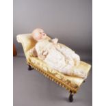 An Armand Marseille porcelain headed doll, 20" high, with chaise longue, upholstered in a yellow and