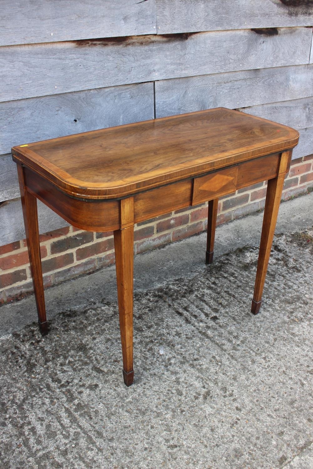 An early 19th century rosewood and satinwood banded fold-over top card table, on square taper