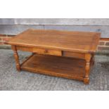 An oak low two-tier coffee table, fitted one drawer, on turned supports, 40" wide x 21" deep x 17"
