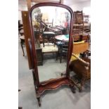 A carved hardwood framed cheval mirror with arch top plate, on plateau base and scroll feet, 30"