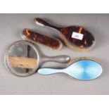 A silver and tortoiseshell backed three-piece dressing table set and another silver and blue